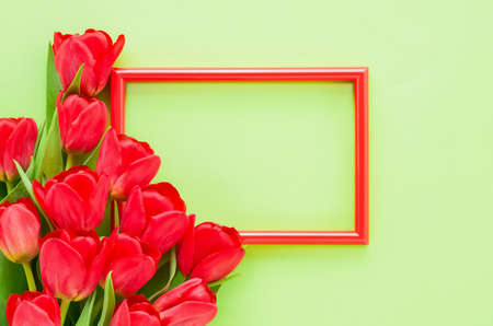 Red frame with red tulips on a green background. Mockup. Top view, copy space for text. Holiday...