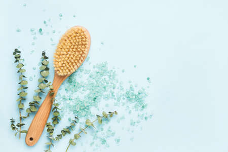 SPA treatment concept. Anti cellulite body brush, eucalyptus branches and bath salt on a blue...
