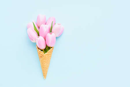 Pink tulips bouquet in waffle ice cream cone on a light blue background. Mothers Day, Valentines Day, bachelorette, summer concept. Copy space, top view. Minimalismの写真素材