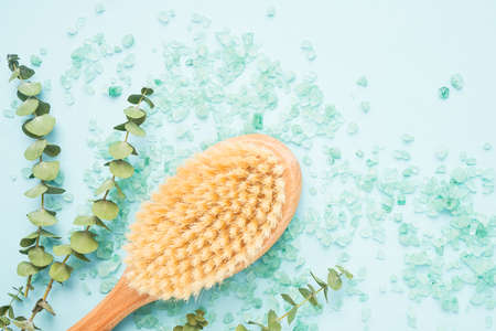 SPA treatment concept. Anti cellulite body brush, eucalyptus branches and bath salt on a blue...