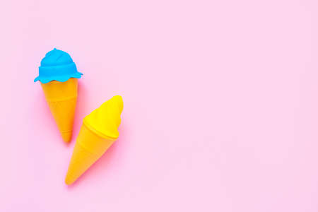 Blue and yellow toy ice-cream on a pink background. Minimalism, summer concept. Top view, copy space...