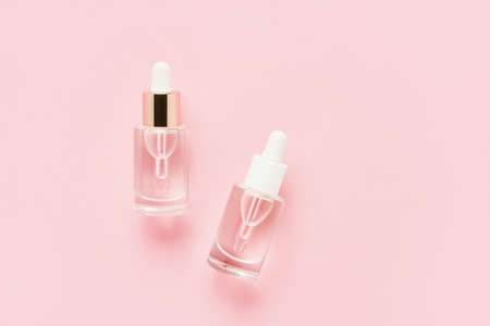Two transparent glass dropper bottles for medical and cosmetic use on pink background. SPA concept. Top view, copy spaceの写真素材