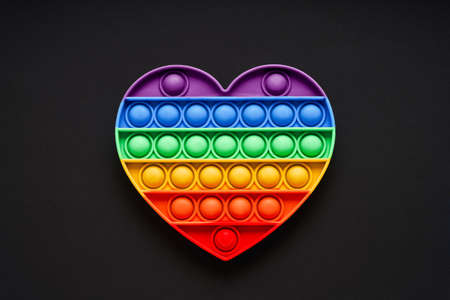 Colorful trendy   heart shape fidgets toy for kids on a black background. Flat layの写真素材