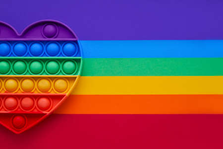 Colorful trendy  heart shape fidgets toy for kids on a rainbow background. Flat layの写真素材