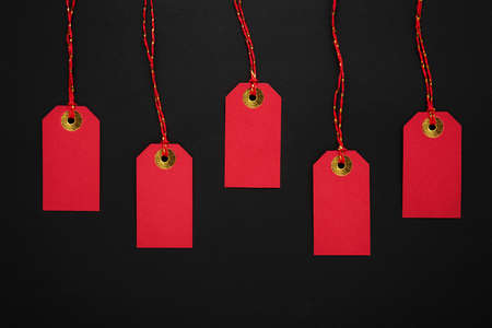 Red sale tags on a black background. Discounts and Black Friday concept. Top view, copy spaceの写真素材