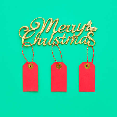 Christmas sales background. Text Merry Christmas and red sale tags on a green backdrop. Top view, copy spaceの写真素材
