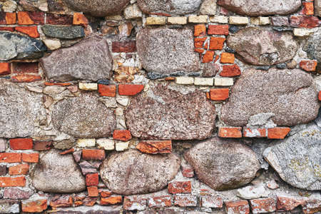 Old red brick wall with cobblestones, grunge background. Copy space