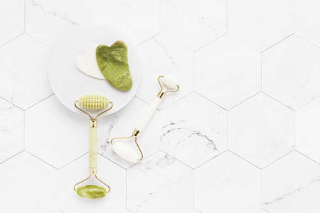 Facial Massage tools. Gua Sha massagers and jade facial rollers on a white marble background. SPA concept. Top viewの写真素材