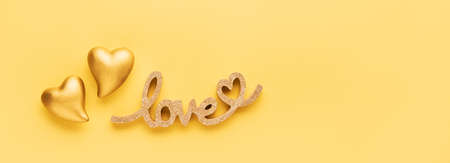 Two golden hearts and word LOVE on a yellow background. Banner. Flat lay, copy space for textの写真素材