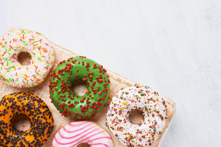 Five colorful donuts on a wooden board. Top view, copy space for textの写真素材