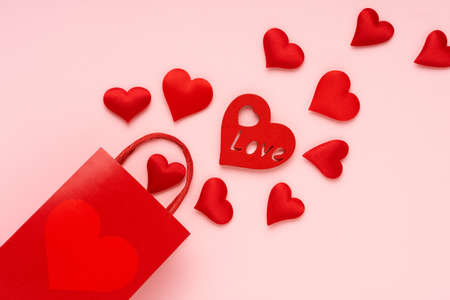 Red gift bag and red hearts on pink background. Valentines day background. Delivery, shopping conceptの写真素材