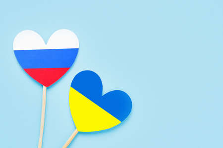 Ukraine and Russian color hearts on a light blue backdrop. Flat lay, copy space