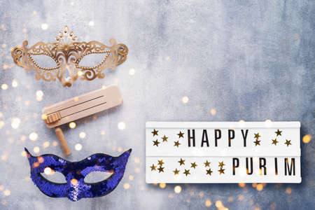 Purim Carnival celebration concept. Happy Purim written in light box, carnival mask and graggerの写真素材