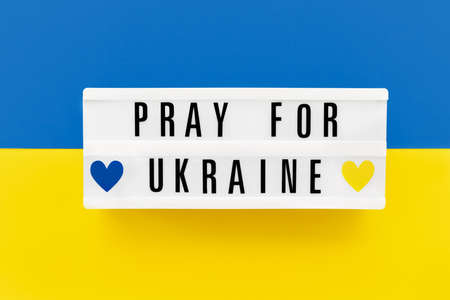 PRAY FOR UKRAINE written in a lightbox on Ukrainian flag colors backgroundの写真素材