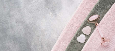 Face Massage tools. Gua Sha massages and rose facial roller on a pink towel. SPA concept. Banner