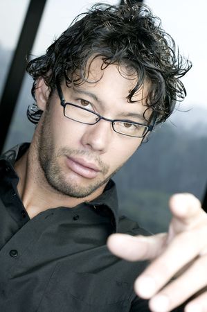 Young man with glasses pointing at the cameraの写真素材