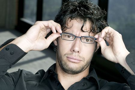 Young man holding his glassesの写真素材