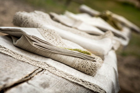 Shot of linen towels, tablecloths, napkins with crochet white and grey lace trim on a wooden benchの写真素材
