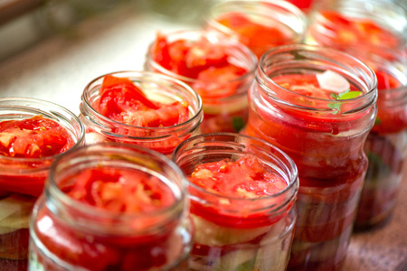 Canning fresh tomatoes with onions for winter in jelly marinade. A shot of basil leaves on top of a red ripe tomato slices and onion rings being put in jar. Fresh food, healthy living, fitness, saladsの写真素材