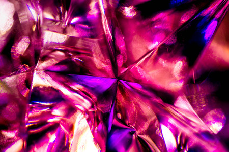 Abstract, blurry, vibrant and colorful background. Macro shot of a purple Christmas star on a lit...