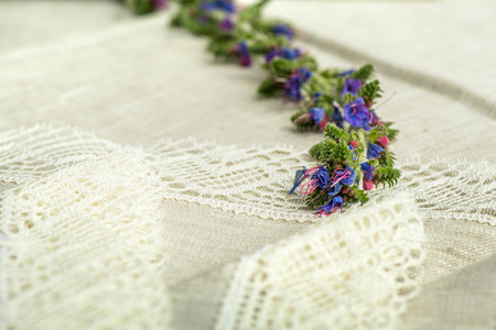 Macro shot of blue flowers on a linen tablecloth with white lace trimの写真素材
