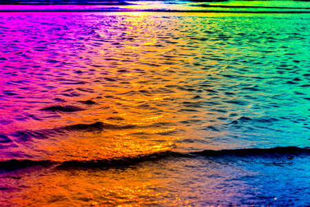 Abstract sea water, small waves, A sunny summer day, romantic walk during sunset. Floating water. Nature is playing with colors. Psychedelic scene. Colorful, vibrant background. Colors of rainbow.の写真素材