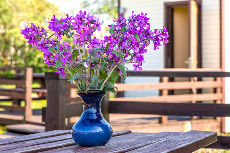 Early summer time. Macro shot of lilac flowers in vase standing on wooden, rustic, vintage table in middle of garden on early morning. Sun is up, perfect day for outdoor activities. Breakfast outsideの写真素材