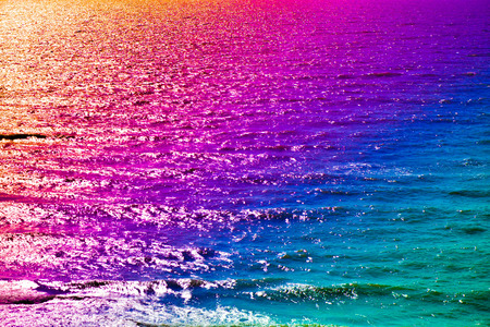 Abstract sea water, small waves, A sunny summer day, romantic walk during sunset. Floating water. Nature is playing with colors. Psychedelic scene. Colorful, vibrant background. Colors of rainbow.の写真素材