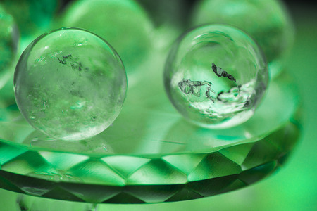 Macro shot of transparent crystal balls with colorful ornaments and sun reflections in it, on turquoise glass pad. Fortune telling. Love, money, luck, success.の写真素材