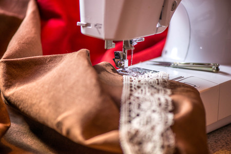 A macro shot of a crochet natural linen lace trim and dark brown linen fabric,being used while...