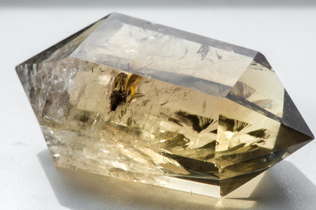 Macro shot of citrine stone on white background. Yellow, clear crystal with a dark, smokey color, smoky quartz with ornaments and rainbows in it. Powerful source of energy and healingの写真素材