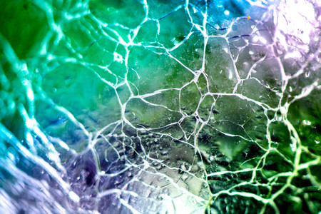 Macro shot of broken, cracked glass ball on colorful rainbow background. Glass reflecting light on sunny summer day. Future prediction, fortune telling in crystal ball. Abstract, esoteric background.の写真素材