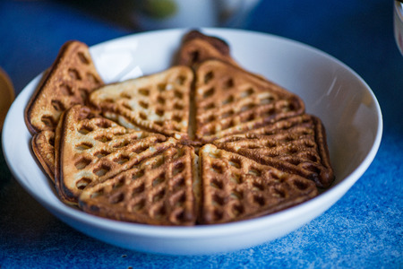 Macro shot of just cooked, delicious, tasty and hot yogurt pancakes with strawberry sauce on yellow and white plates in kitchen, next to stove. Dinner is ready. Sweet golden brown waffles with jam.の写真素材