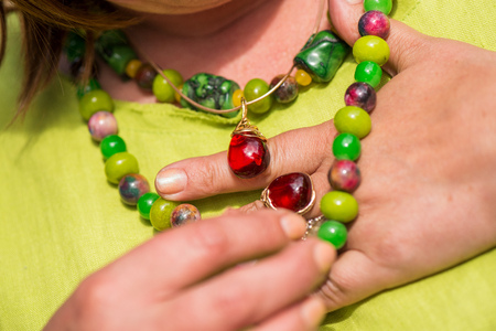 Woman wearing beautiful gemstone necklace and golden ring with amber. Jewelry made of coral, olivine and agate stones. Powerful energy of healing crystalsの写真素材