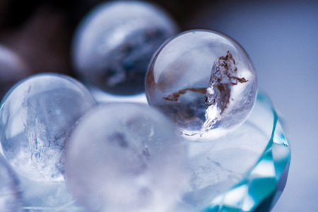 Macro shot of transparent crystal balls with colorful ornaments and sun reflections in it, on turquoise glass pad. Fortune telling. Love, money, luck, successの写真素材