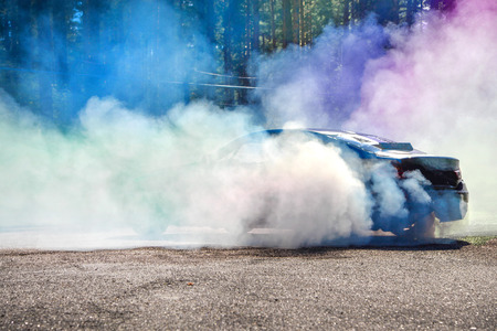 Drift car warming up the tires before  start, waiting for race to begin. Blue and purple smoke all...