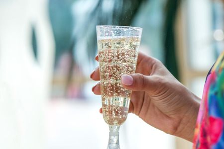 New year celebration. Girl in beautiful colorful dress is holding a champagne glass full of sparkling wine. Cheerful bride and bridesmaids partyの写真素材