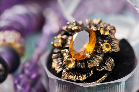 Macro shot of silver engagement ring in gift box on colorful, sparkling background. Ring made of yellow sapphire and citrine stone. Healing, natural crystals and powerful energyの写真素材