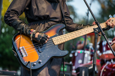 Young female rock music artist playing electric guitar on stage on evening. Band performing their songs. Music festivals in summer. Live hard rock and metal musicの写真素材