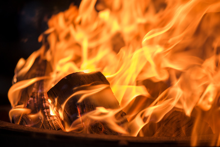 Burning bonfire with soft glowing flame and sparkles flying all around. Romantic summer evening. Preparing grill for barbecue partyの写真素材