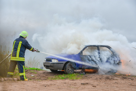 Fire fighter prepare to attack a propane fire. Burning and crashed car after explosion. Accident on...