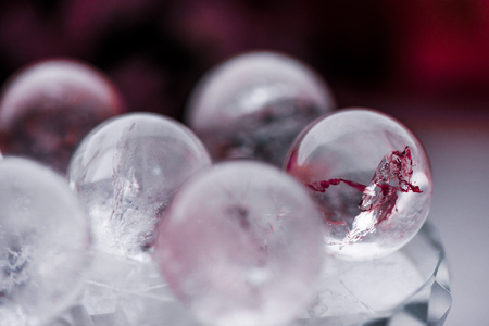 Macro shot of transparent crystal balls with colorful ornaments and sun reflections in it, on turquoise glass pad. Fortune telling. Love, money, luck, success.の写真素材
