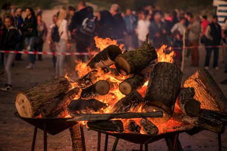 Large burning bonfire with soft glowing flame and sparkles flying all around. Romantic summer evening, people relaxing and enjoying calmness at the seaside during the Night of ancient lights.の写真素材