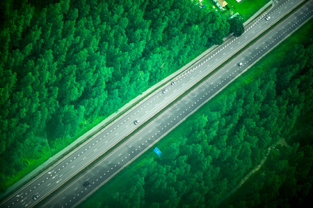 Aerial shot from plane of highway road and foggy forest on both sides. Cars are driving fast