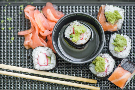 Fresh and delicious maki and nigiri sushi rolls with tiger shrimps, salmon, philadelphia cheese and wasabi served with soy sauce and ginger slices on black take away plate. Japanese food in restaurantの写真素材