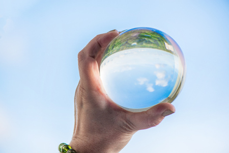 Woman's hand with gemstone bracelet holding large crystal ball with world reflection in it. Esoteric background, healing and powerful crystal energyの写真素材