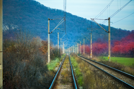 Eastern European railroad across Transilvania. Mountain landscape in the background. Scary, dangerous scene in winter with naked trees and polluted natureの写真素材