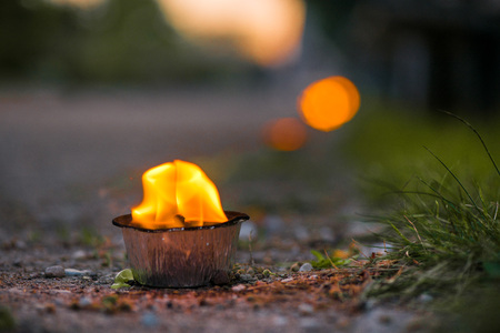 Macro shot of lit candle burning with soft glowing flame and smoke on evening background. Candle path at the park close to the seaside during the Night of ancient lights.の写真素材