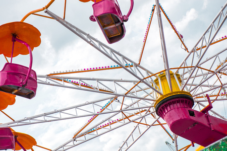 Colorful roller coaster seats at amusement park. People having fun in carousel. Wheel is spinning fast.の写真素材