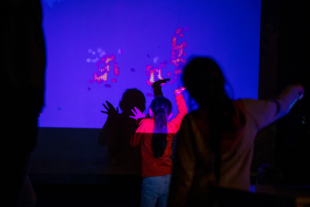 Abstract, blurry new technology background. Little girl is playing with interactive visual...